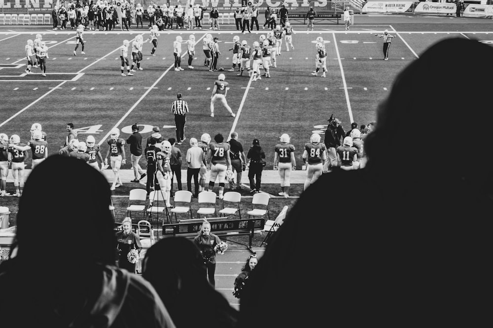 grayscale photography of group of men playing soccer surrounded with people watching them