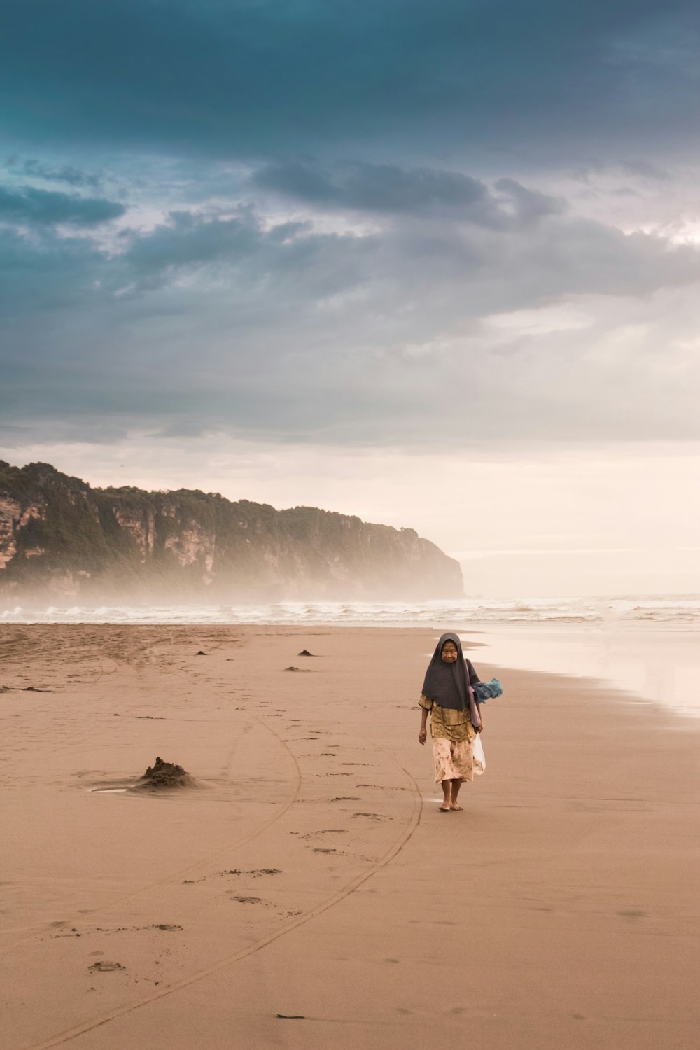 a person walking on a beach with a surfboard