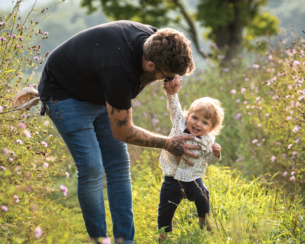 man wearing black crew-neck t-shirt standing and about to carry baby