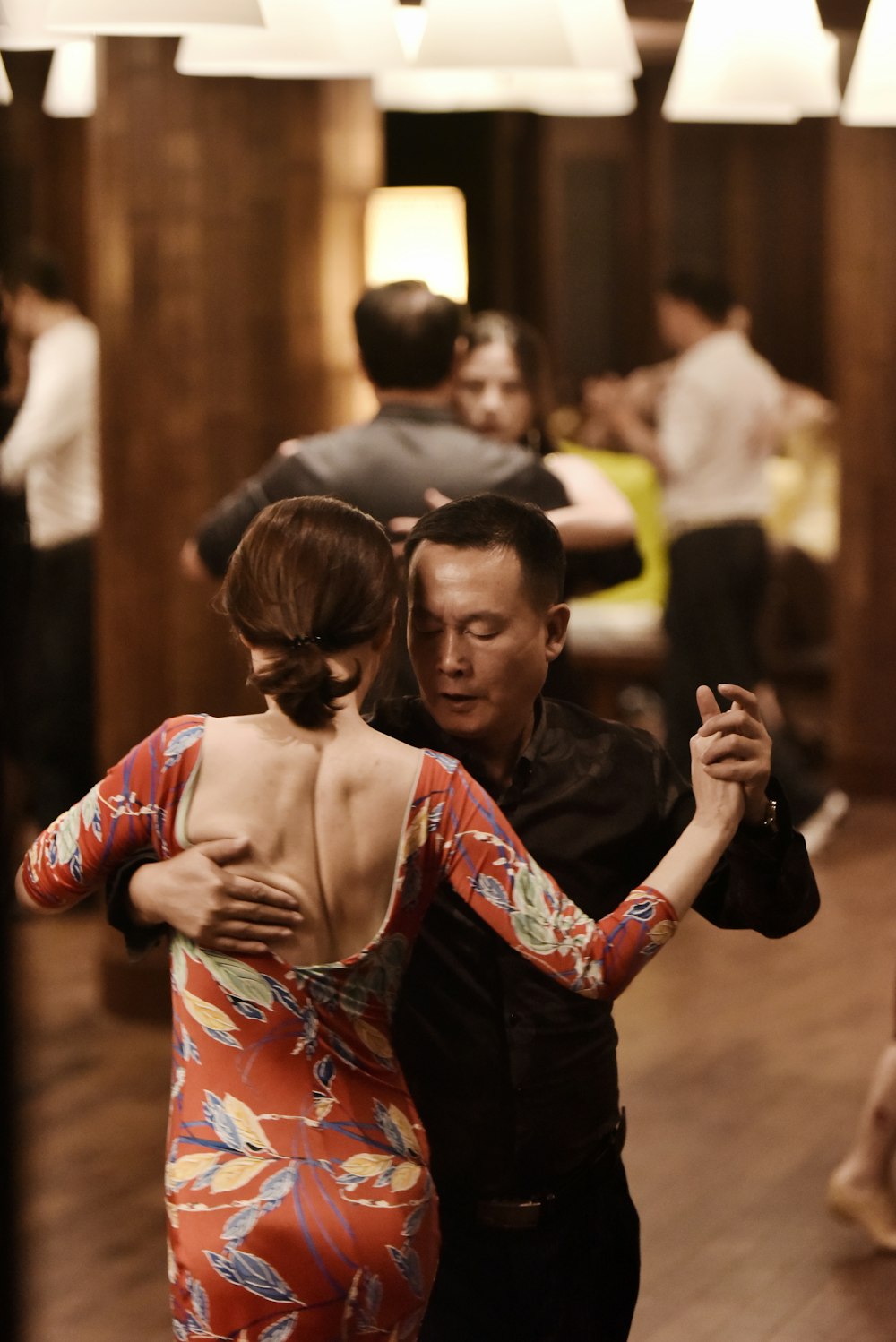 man and woman dancing with woman in red and gray dress