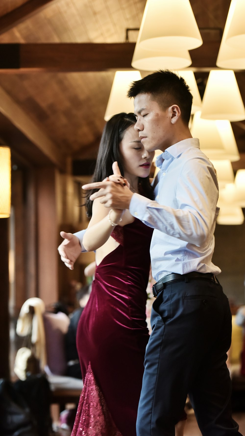 man in white shirt dancing with red velvet dress inside a lighted room