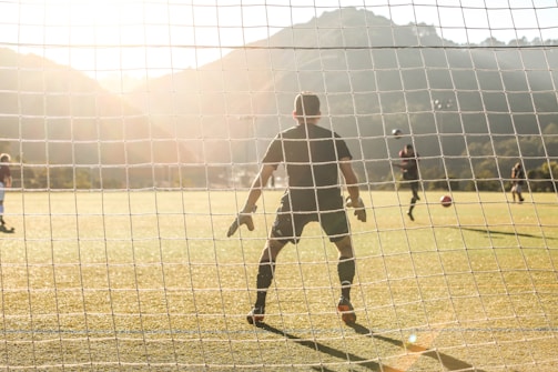 A coach reviewing game footage with players on a sunny soccer field.