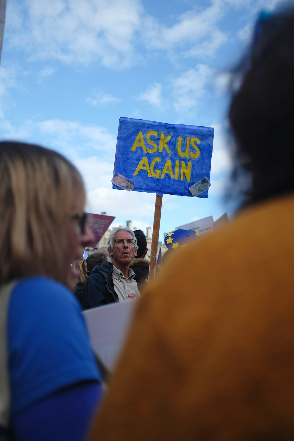 a woman holding a sign that says ask us again