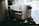 A stainless steel pot boiling with steam rising on a gas stove in a kitchen setting. The pot is prominently placed, while the background features blurred kitchen elements.