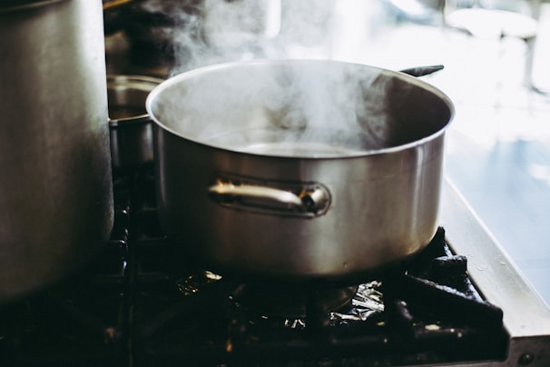 A sleek stainless steel saucepan simmering on a modern stovetop with steam rising