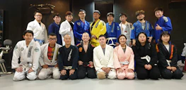 A group photo of diverse martial arts students smiling proudly in their gis after training.
