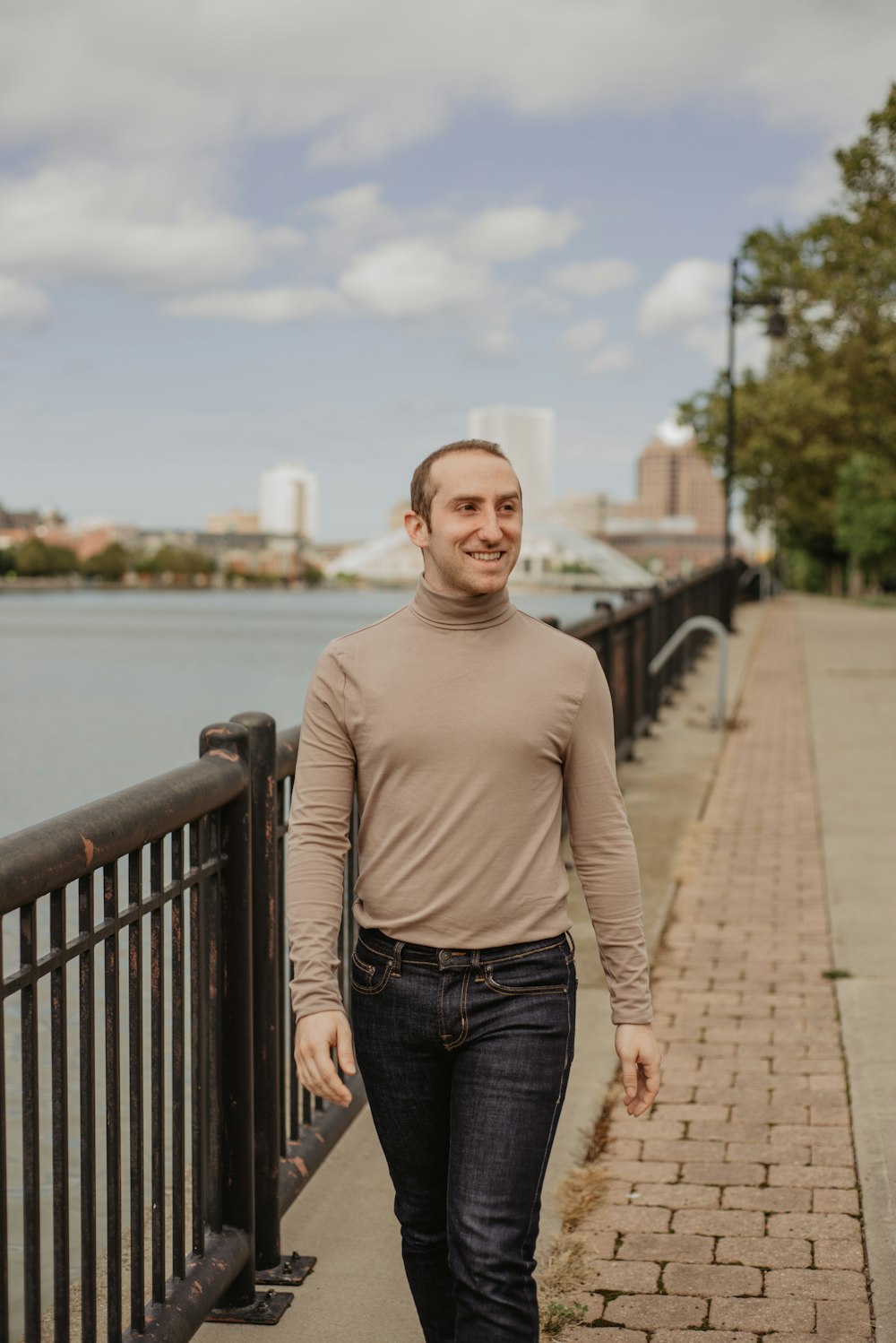 man in gray sweater walking beside body of water