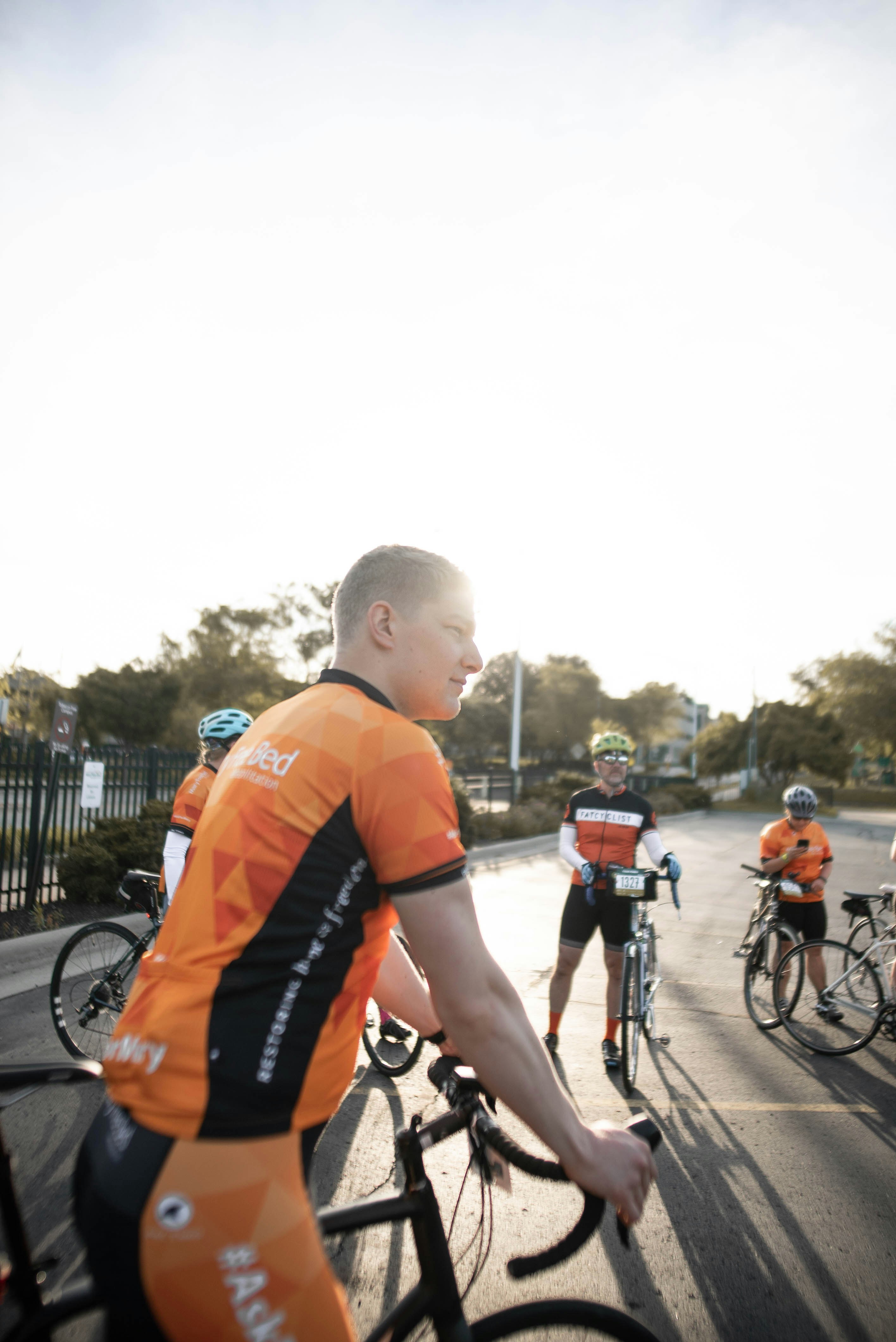 man in orange top riding road bike