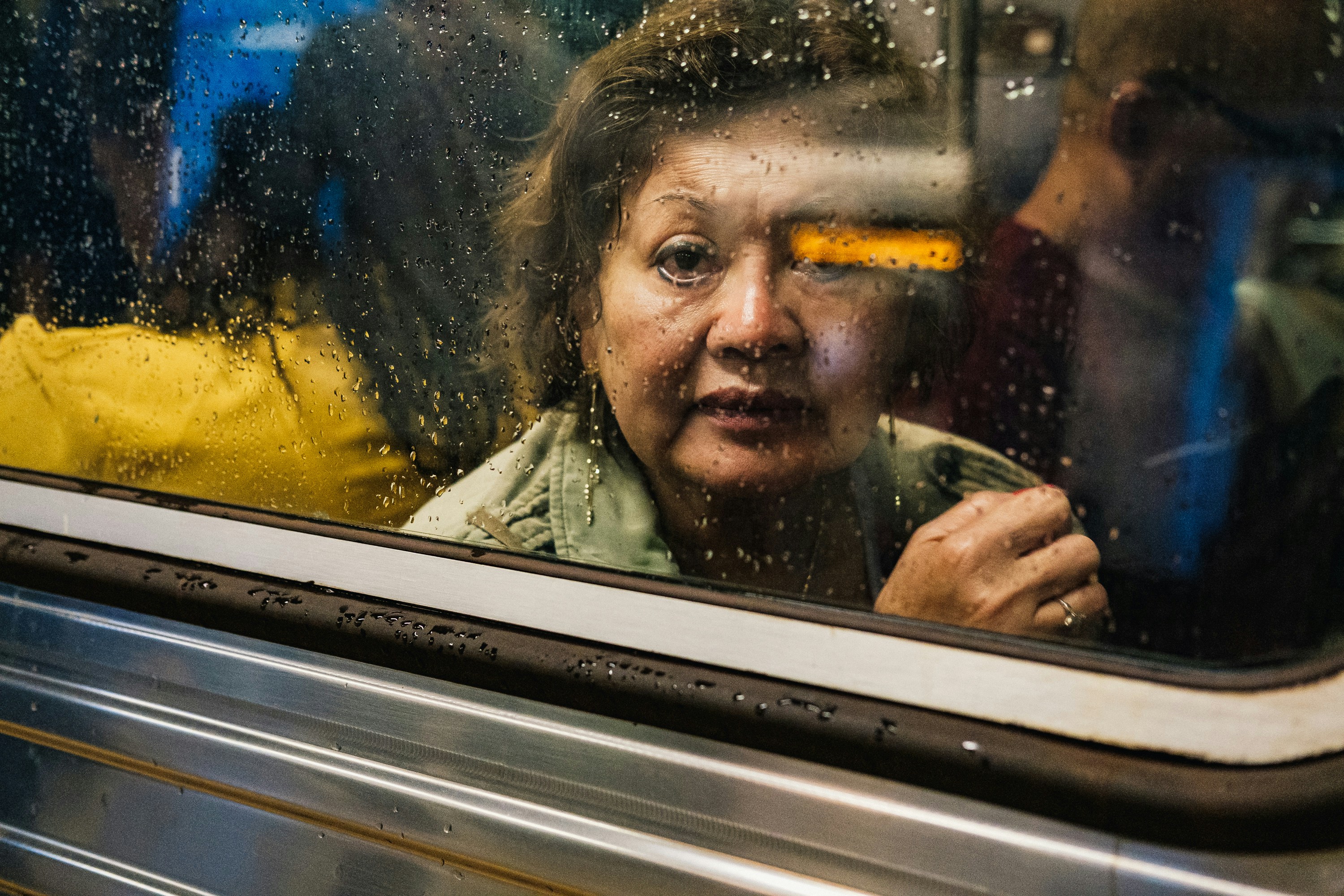 Woman looking out rainy café window, reflection of street overlapping her face