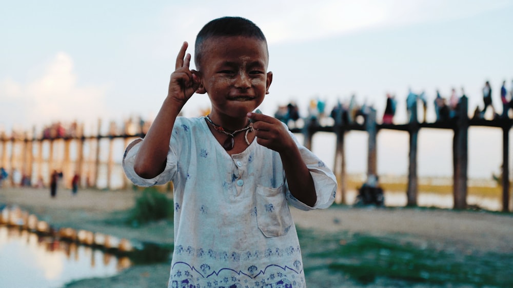 a young boy standing in front of a body of water