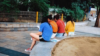 A diverse group of people reading newspapers and using digital devices outdoors.