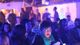 A group of volunteers sharing knowledge and supplies under soft blue and purple lighting.