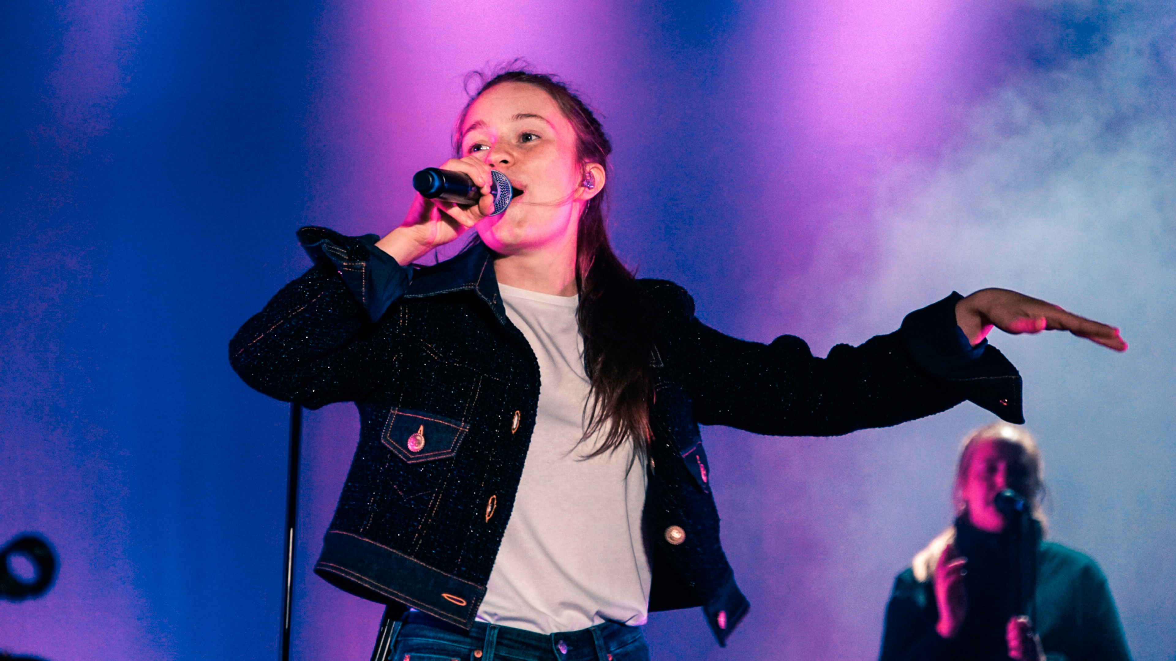 woman wearing black jacket standing and singing