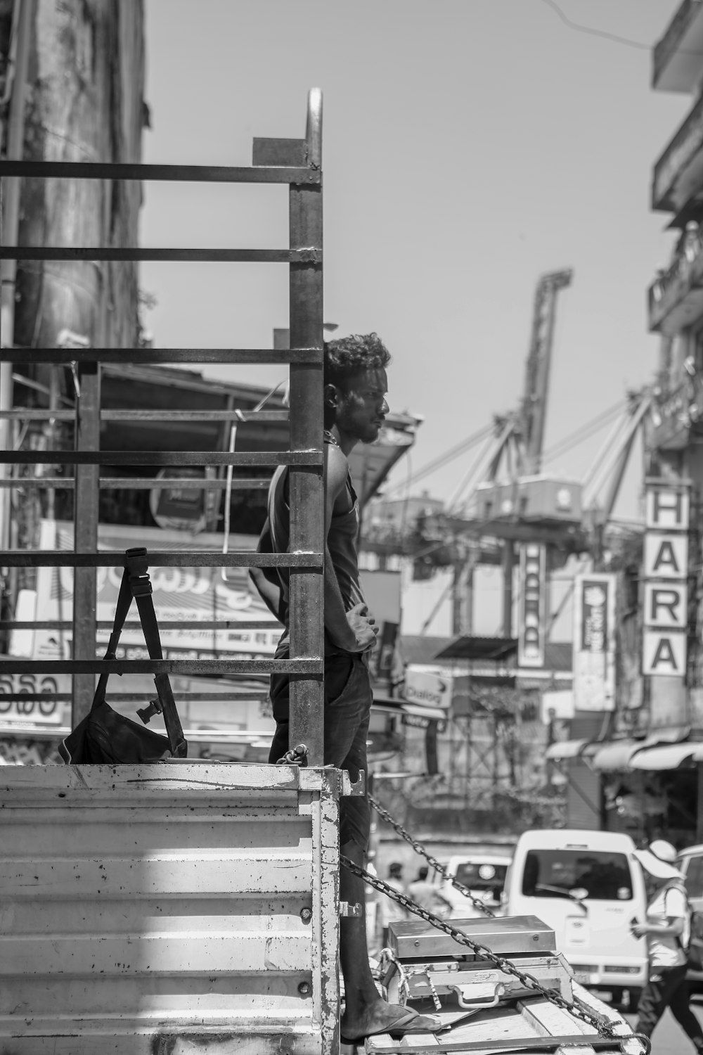 grayscale photography of man standing near post
