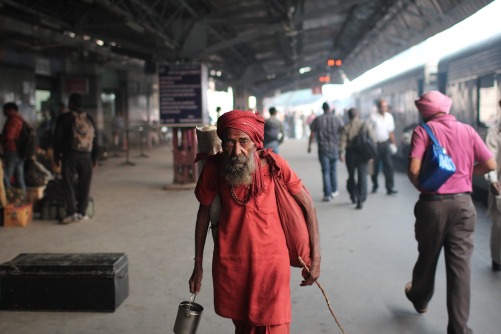 man in red coat and red knit cap holding silver steel container