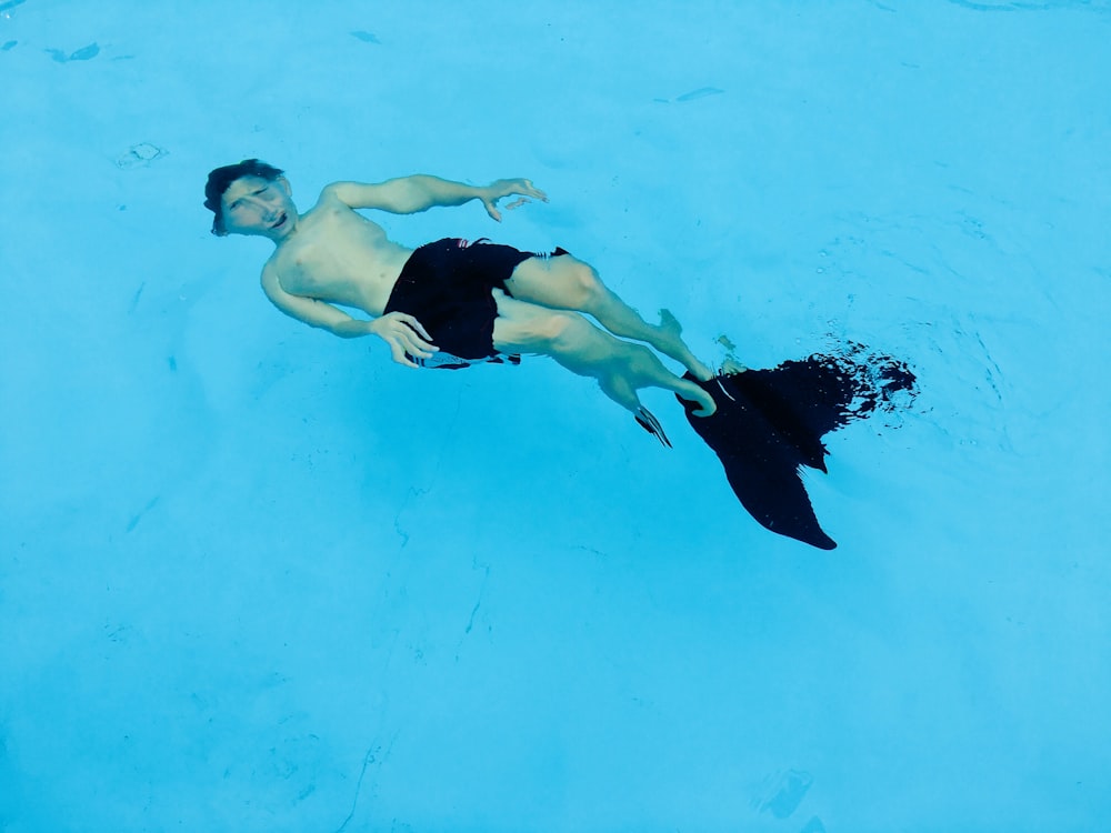 泳いでいる間、黒いショートパンツと足ひれを身に着けている男