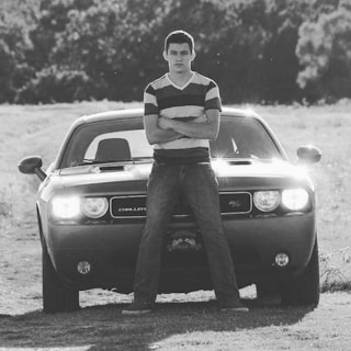 Portrait of a confident drift driver standing next to his customized E30 car.