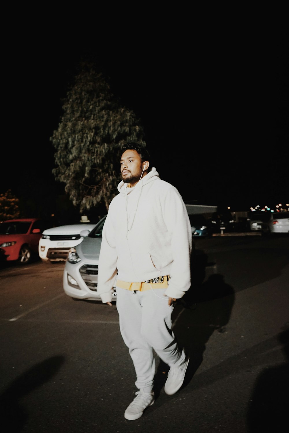 man in white jacket and white pants walking outdoors