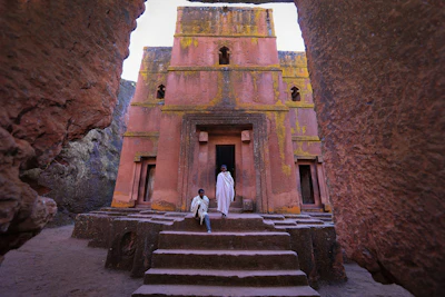 person in white dress in front of pink building