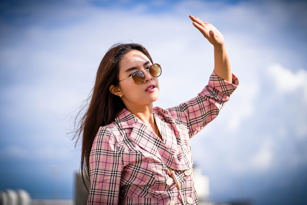 woman raising her left hand wearing sunglasses