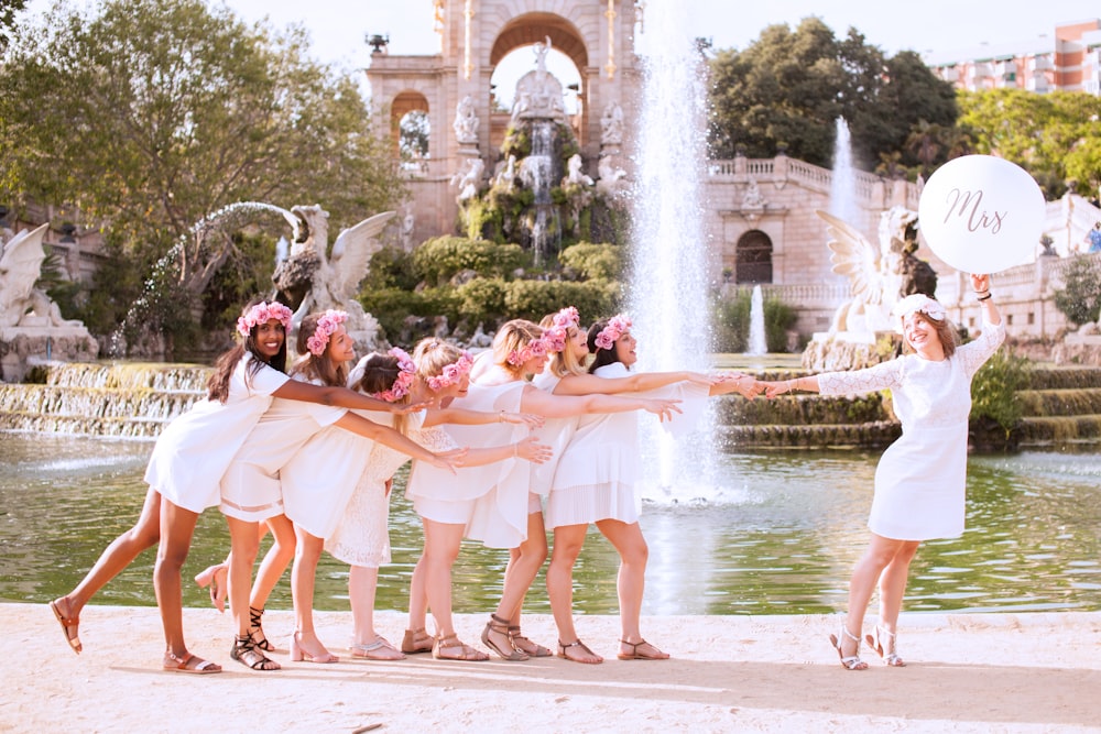 group of women holding woman near body of water