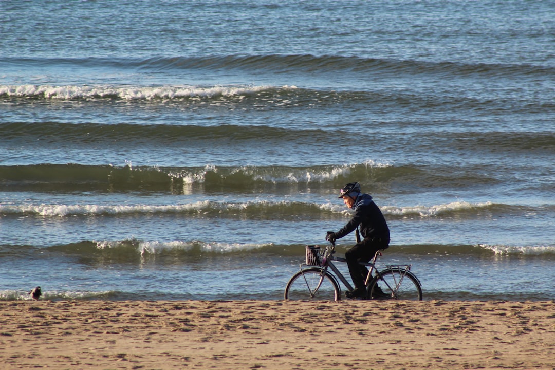 man riding bicycle beside seashore during daytime