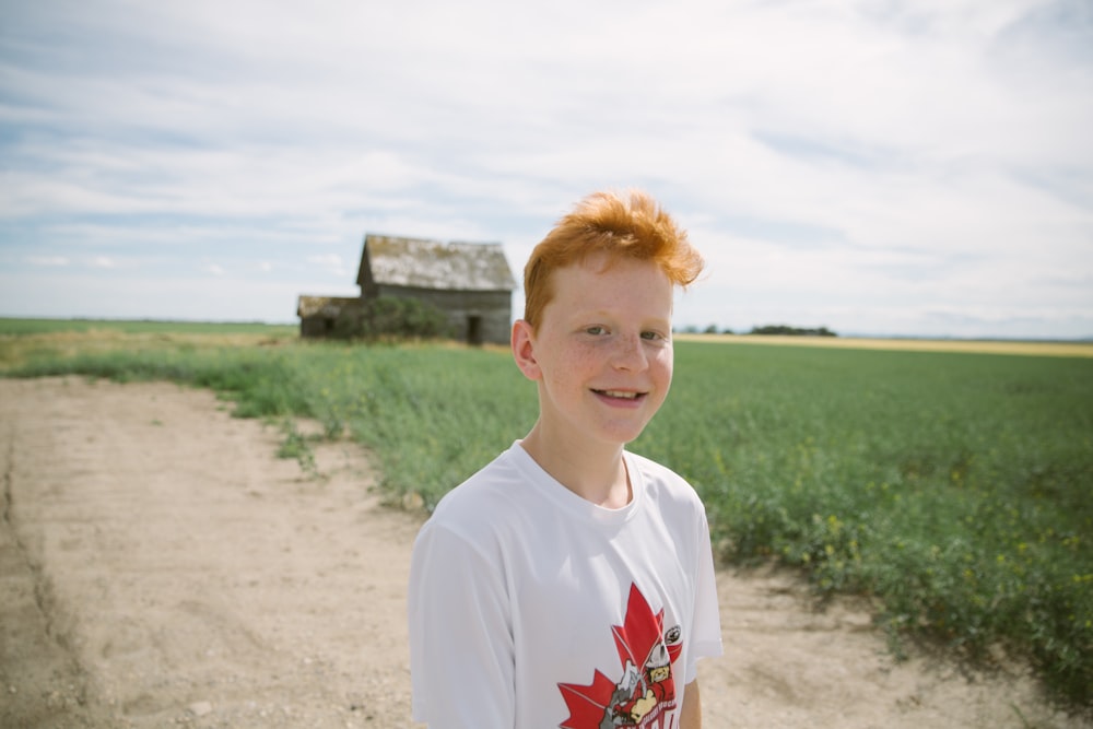 smiling boy standing near gray wooden house