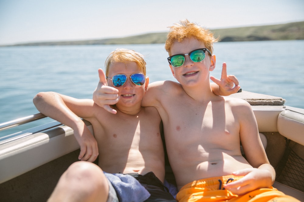 two topless boy sitting on body