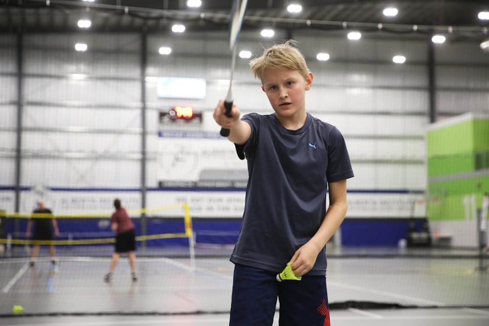 Junge zeigt einen Badmintonschläger vor sich