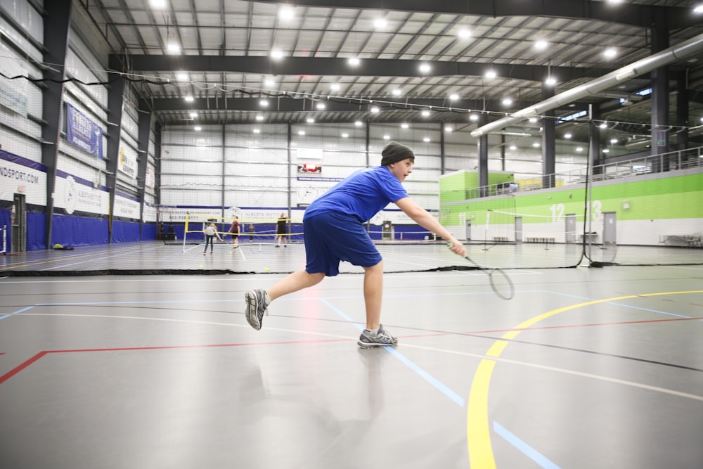 man playing badminton inside gymnasium