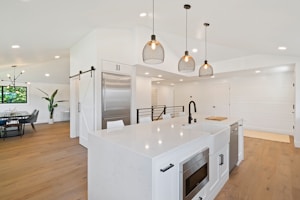 A sleek kitchen featuring bright, energy-efficient pendant lights over the island.
