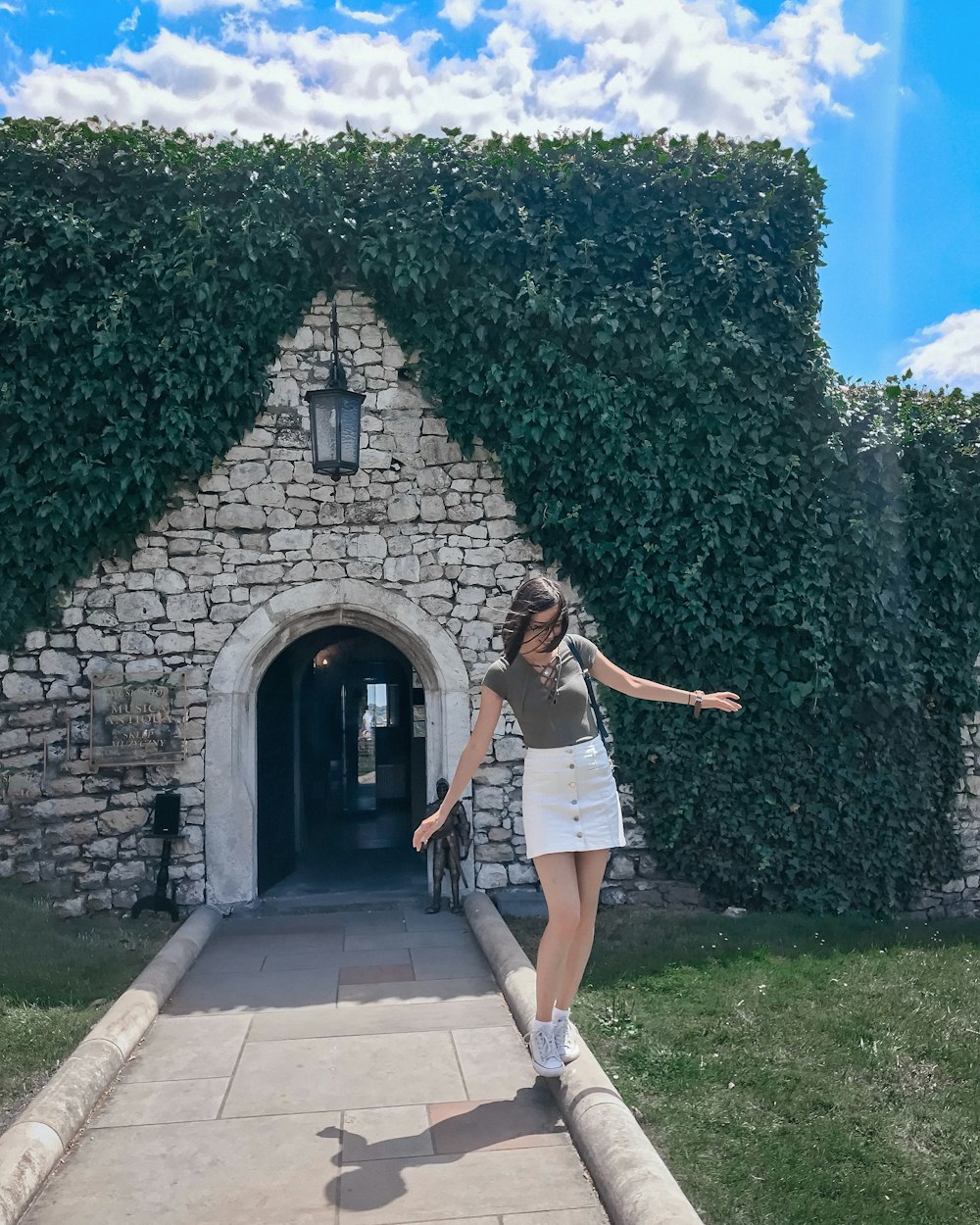 woman balancing on pathway railing in front of brick building