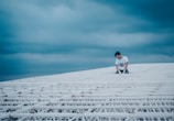An athlete pausing in deep reflection on a city rooftop under a vast midnight blue sky.