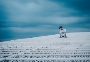 An athlete pausing in deep reflection on a city rooftop under a vast midnight blue sky.