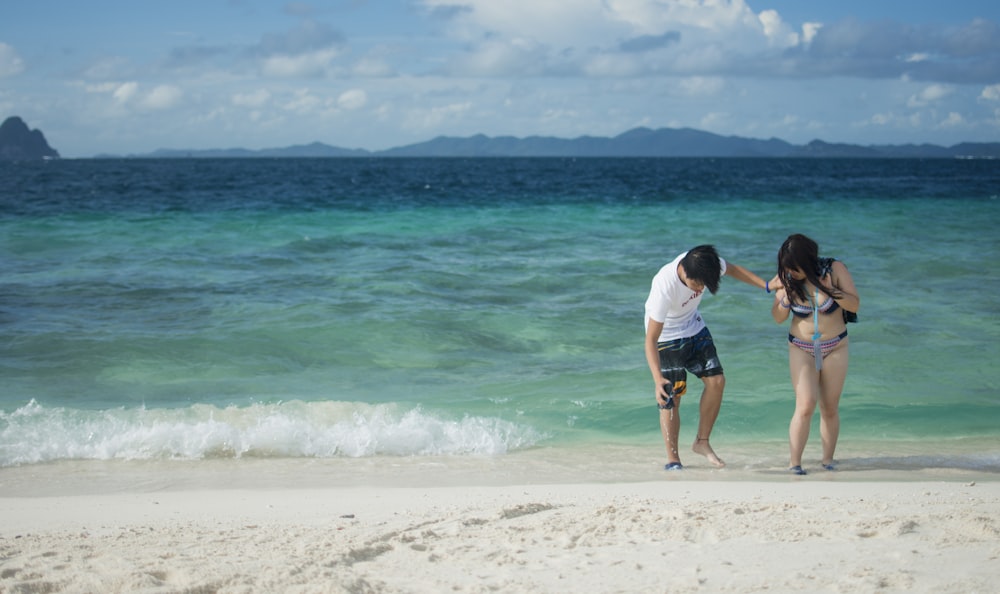 man and woman standing on shore at daytime