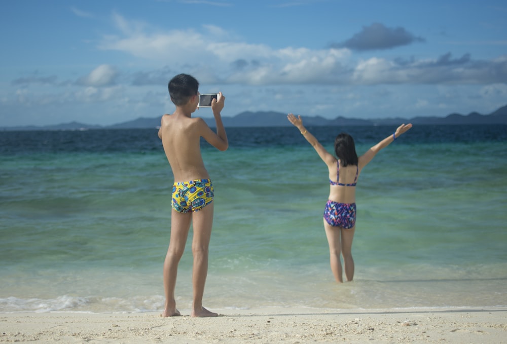 homem que tira a foto da mulher em pé na praia