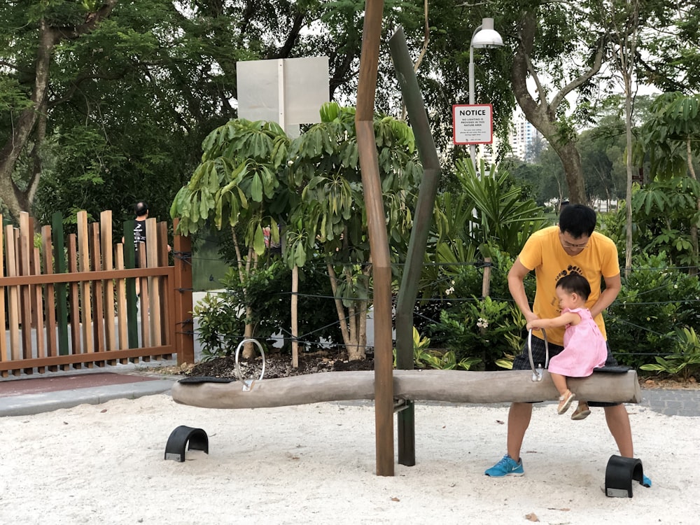 man holding child sitting on seesaw