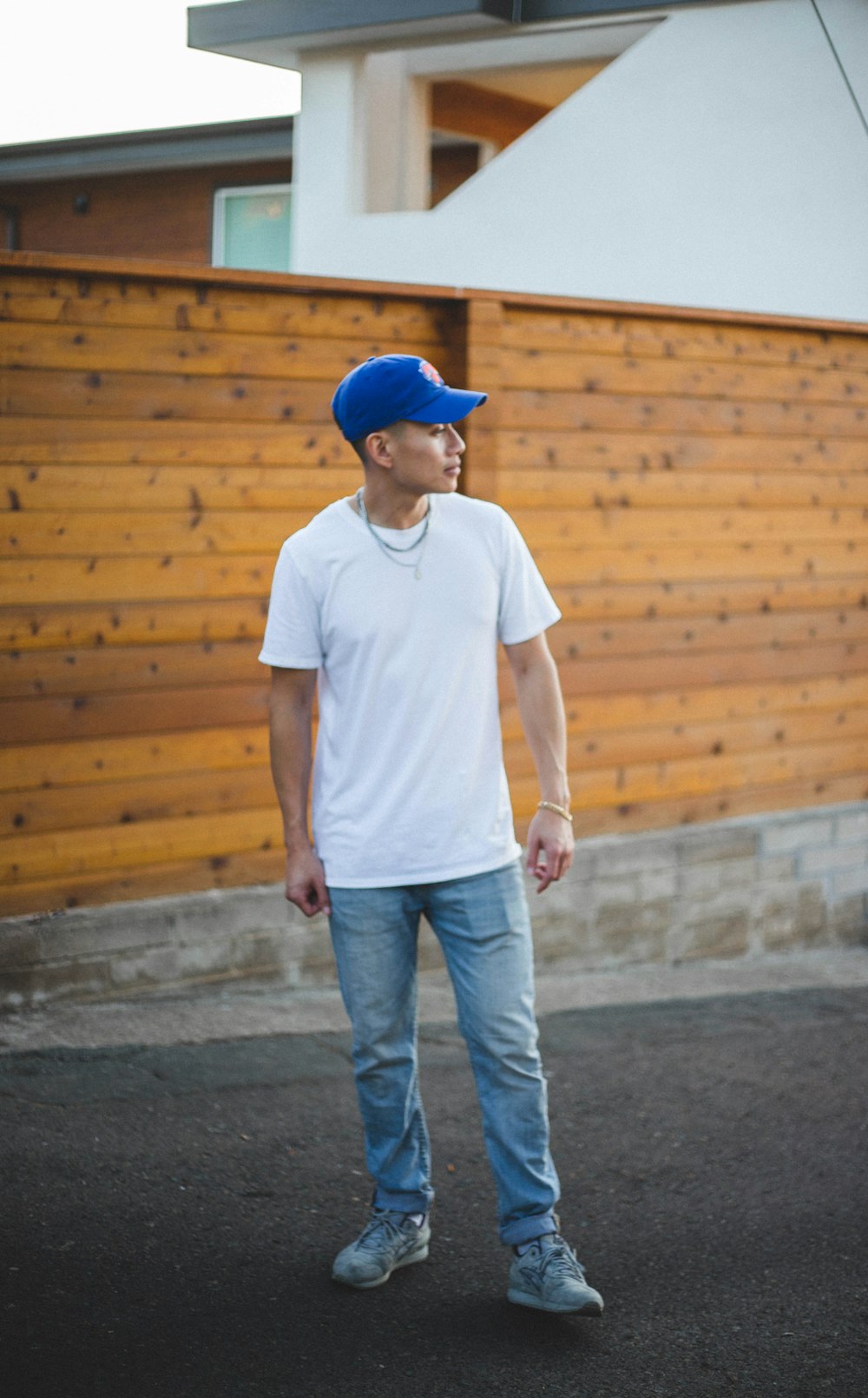 man in white crew neck t-shirt and blue denim jeans standing on gray concrete floor