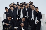 A group shot of men in black and white tailored garms, posing confidently on concrete steps