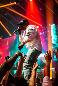 Tomy Jabana performing on stage with vibrant lights and an energetic crowd.