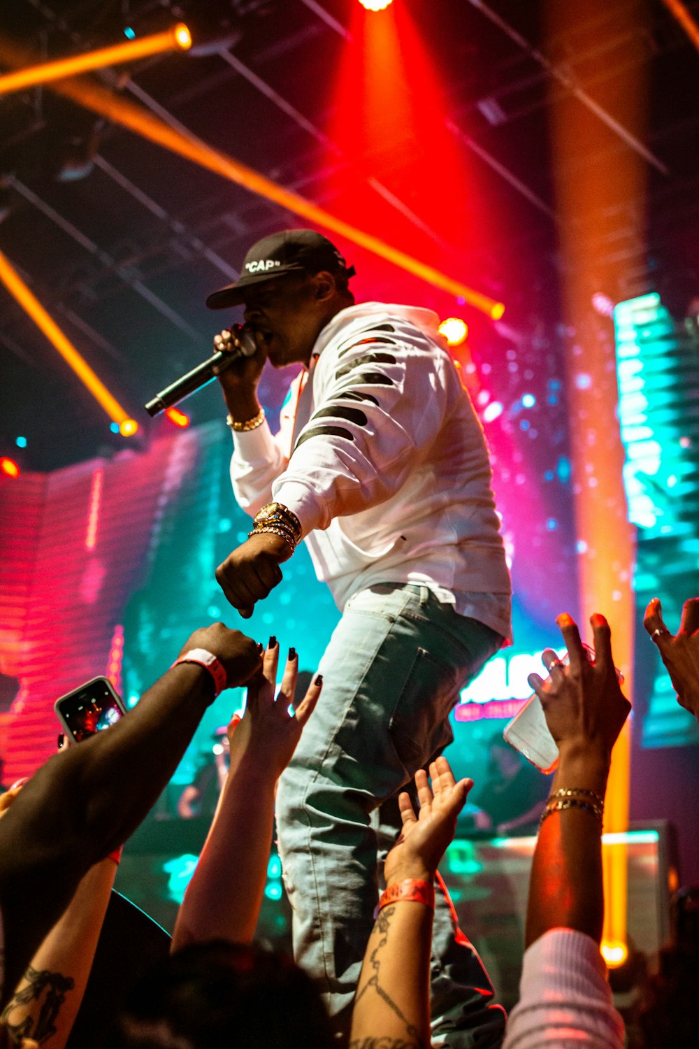 man in white long sleeve shirt and green camouflage pants singing on stage