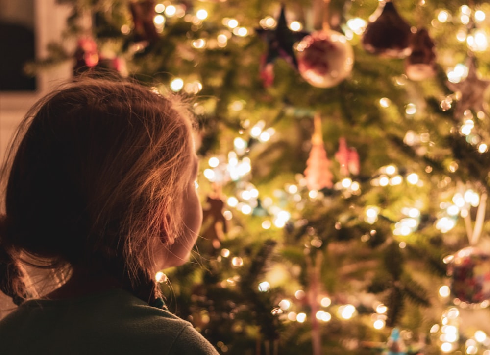 Dievča pred rozžiareným vianočným stromčekom.