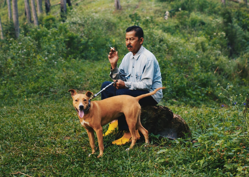 man sitting and holding leash of a dog