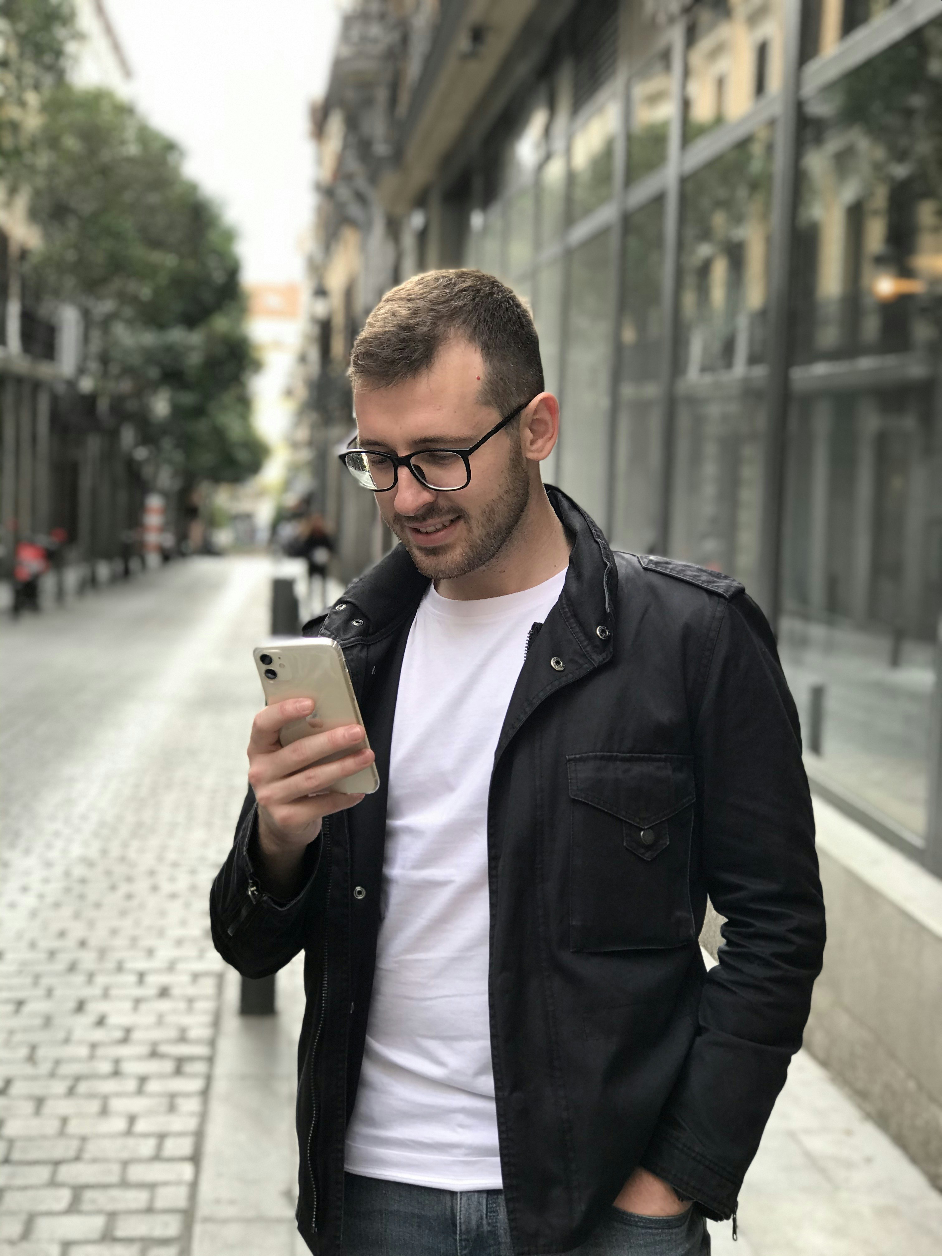 man in black full-zip jacket using smartphone