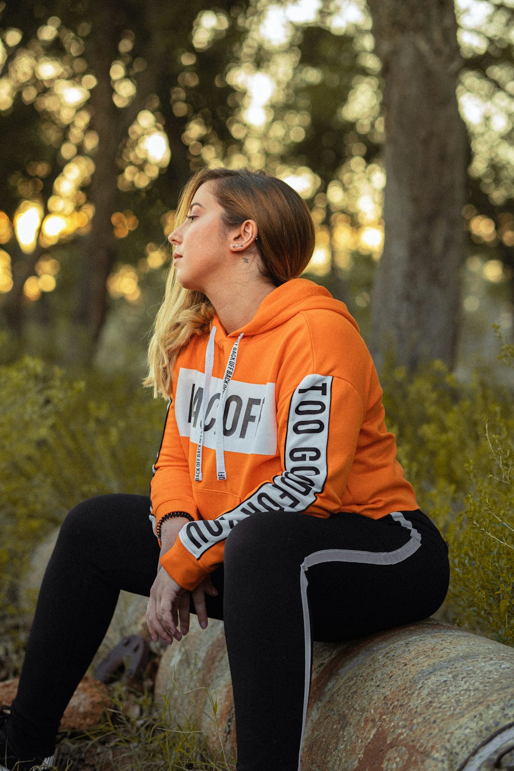 woman sitting on log in over hoodie