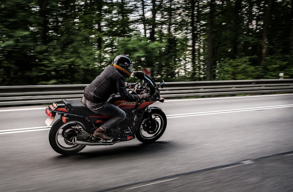 man riding motorcycle on road near trees