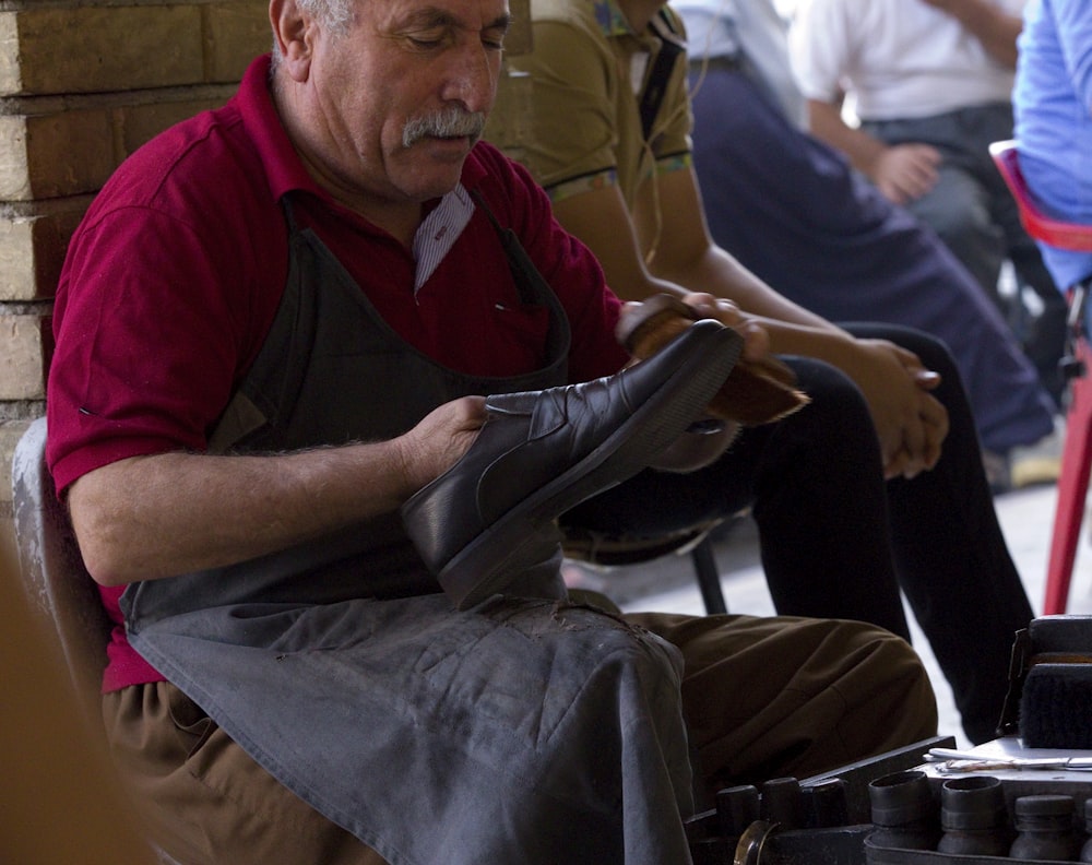 hombre sosteniendo un zapato con delantal negro