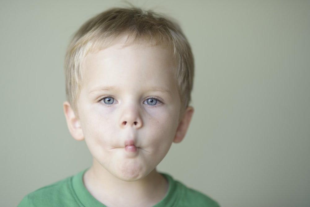 shallow focus photo of boy in green crew-neck shirt