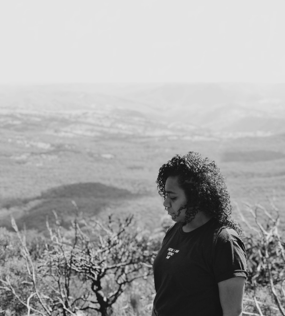 Foto en escala de grises de mujer al lado de las plantas