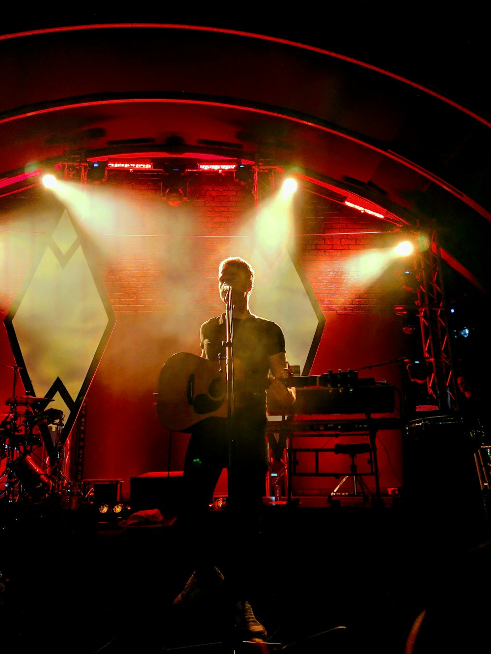 man with guitar performing on stage with lights